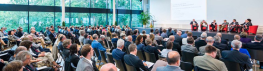 Gefüllter Tagungssaal mit Diskussion auf dem Podium