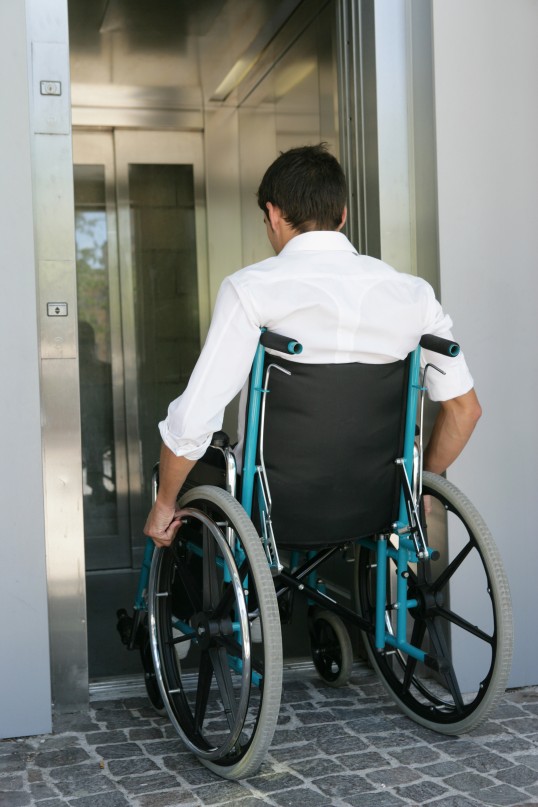 ein Rollstuhlfahrer fährt in einen Aufzug