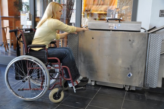 Frau im Rollstuhl bedient einen behindertengerechten Treppenlifter