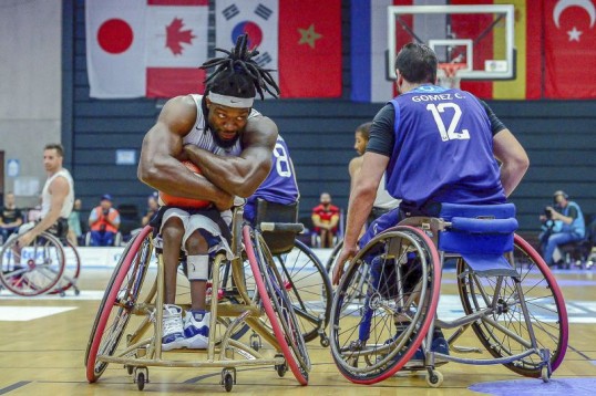 Foto von Uli Gasper zeigt zwei Rollstuhl-Basketballer. Einer klammert sich am Ball und schaut Gegner verschmitzt in die Augen
