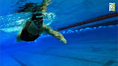 Unterwasseraufnahme zeigt Schwimmerin komplett unter Wasser, schwimmt auf Kamera zu.
