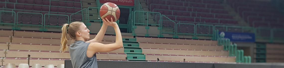 Lilly Sellak in der Sporthalle, dabei, einen Basketball zu werfen. 