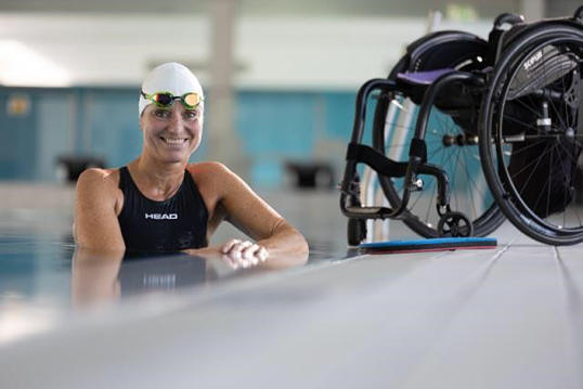 Kirsten Bruhn im Schwimmbecken, am Rand steht ihr Rollstuhl