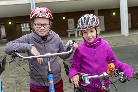 zwei Schulkinder mit Fahrradhelm und Fahrrädern