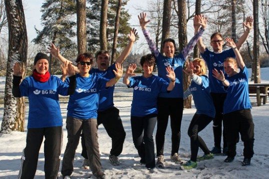 Bild zeigt Mitarbeitende der BG RCI mit zum Gruß erhobenen Händen. Es liegt Schnee, die Personen tragen Sportkleidung.