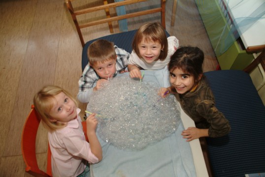 Am Tisch sitzende Kinder erstellen eine riesigen Berg von Seifenblasen