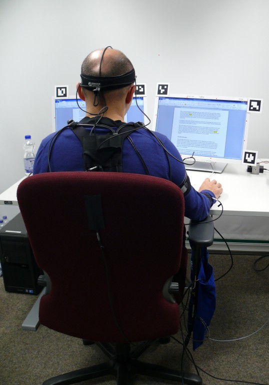 Test person equipped with measurement system working at two screens