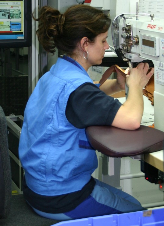 Sewing operative working in seated position at the modiefied workplace