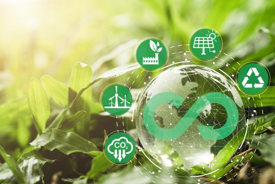 Augumented reality picture that shows greenery and multiple bubbles that each contain symbols, e.g. the infinity symbol combined with the recyling symbol, and symbols for solar systems, wind power and ecological industry 