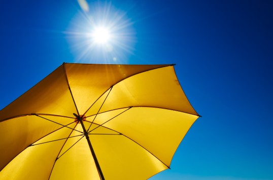 Foto eines gelben Sonnenschirms vor einem blauen Himmel