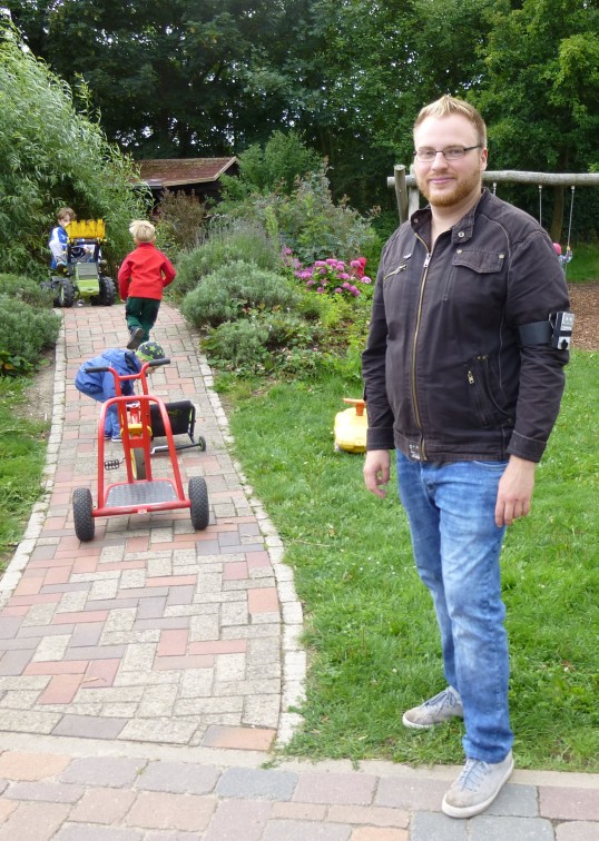 Mann mit Oberarmmessgerät und Kinder im Garten