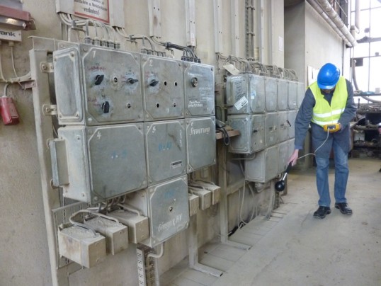 Picture of a low-voltage distribution installation and a man measuring the electromagnetic fields
