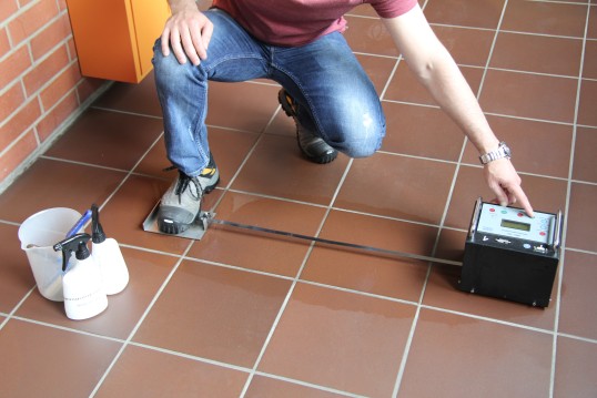 Tester testing the slip-resistance on a pool of liquid