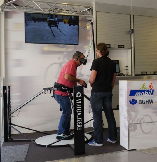 Picture of a person on an omnidirectional treadmill wearing VR glasses with a head mounted display during a warehouse simulation 