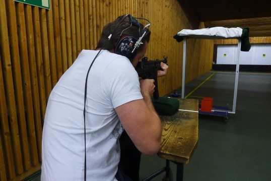 Foto: Schütze mit Kopfhörern der gerade mit seiner Schusswaffe auf eine Glasscheibe zielt