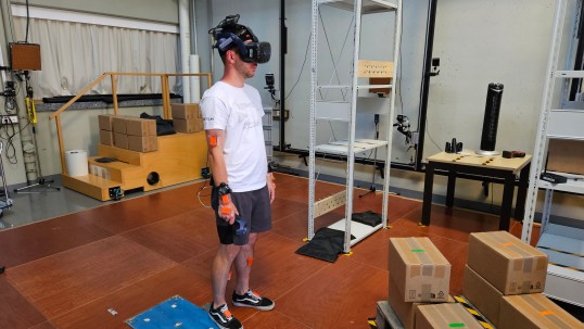 Foto einer Person, die das CUELA-Rückenmonitor sowie eine VR-Brille trägt.
