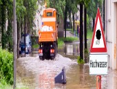 Bild einer überfluteten Straße und einem orangen LKW.