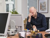 Erschöpfter Mann am Schreibtisch vor Monitor