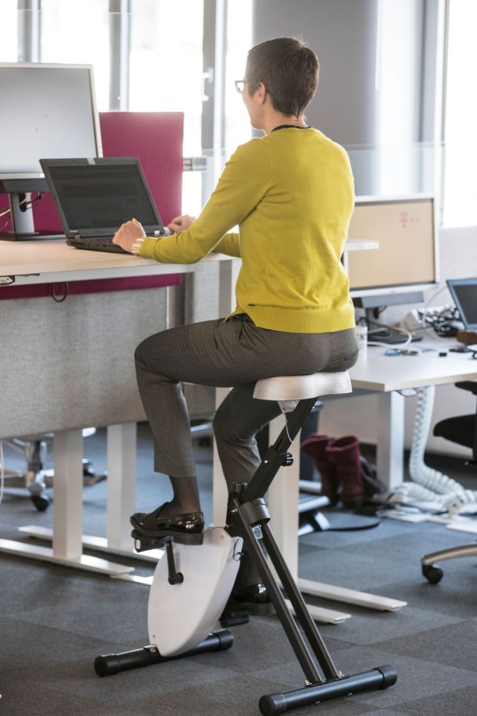 Mitarbeiterin auf Deskbike bei der Bildschirmarbeit