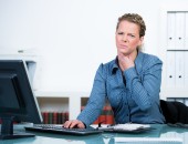 Bild einer Person vor dem Laptop, die sich an den Hals fasst.