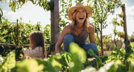 Person sitzt in ihrem Garten, im Hintergrund sitzt ein Kind.