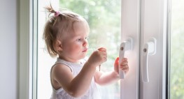 Bild eines Kleinkindes, das einen Fenstergriff anfasst.