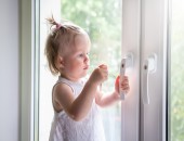 Bild eines Kleinkindes, das einen Fenstergriff anfasst.