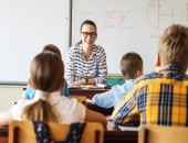 Lehrerin vor mehreren Schülern im Klassenraum 