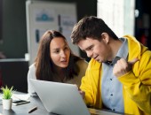 Eine junge Frau erklärt einem jungen Mann etwas am Computer.