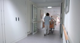 Zwei Personen schieben ein Krankenhausbett durch eine Tür.