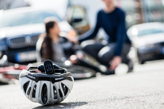 Eine Radfahrerin liegt am Boden, im Vordergrund liegt ein Fahrradhelm