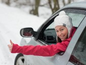 Bild einer Person, die bei schneebedeckter Straße im Auto sitzt, und den Kopf und den Arm aus dem Fenster hält.