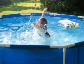 Ein Kind spielt in einem blauen Gartenpool.