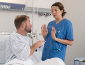 Bild eines Patienten und einer Pflegekraft, zwischen denen ein Konflikt herrscht. Die Pflegekraft halt die Hände vor den Körper.
