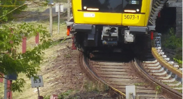 Bild einer Bahnstrecke, ein gelber Zug fährt auf der Schiene.