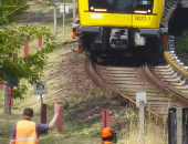 Bild einer Bahnstrecke, ein gelber Zug fährt auf der Schiene.