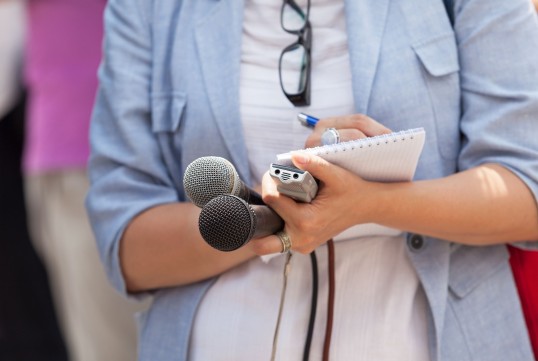 Journalistin mit Mikrofon und Notizblock 