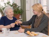 Foto: Eine junge Frau hilft ihrer Großmutter beim Essen