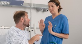 Foto: Ein Patient in einem Krankenhausbett beschimpft eine Pflegerin.