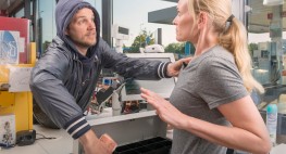 Foto: ein Mann greift in die Kasse einer Tankstelle und bedroht die zurückweichende Angestellte