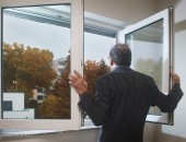 Foto: Ein Mann öffnet ein Fenster zum Stoßlüften
