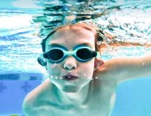 Foto: schwimmender Junge schaut unter Wasser in die Kamera