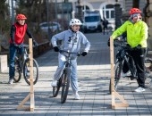 Foto: drei Personen mit Fahrradhelm üben auf einem Fahrradparcour
