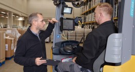 Foto: ein Mann mit einem Tablet in der Hand spricht mit einem Fahrer eines Gabelstaplers