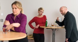 Foto: eine Frau und ein Mann machen sich hinter ihrem Rücken - aber hörbar - über eine Kollegin lustig