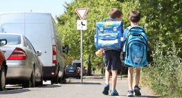 Foto: zwei Kinder gehen an parkenden Autos vorbei zur Schule