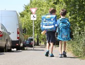 Foto: zwei Kinder gehen an parkenden Autos vorbei zur Schule