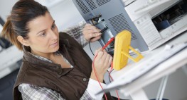 Bild: Eine Technikerin prüft den Stromfluss an einem Computer