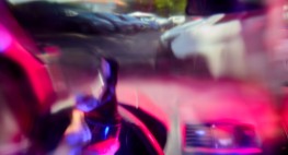 Foto: Verzerrter Blick durch eine Auto-Windschutzscheibe - mit einer Flasche Bier in der Hand und am Lenkrad