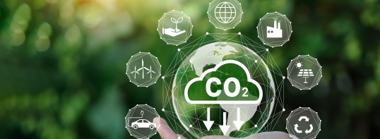 Bild mit einer CO2 Blase und darum sieben Symbolen wie Elektromobilität, Windenergie, Nachwachsende Rohstoffe, globales Kreislaufsystem, Industrie, Erneuerbare Energien (Solar) und Recycling